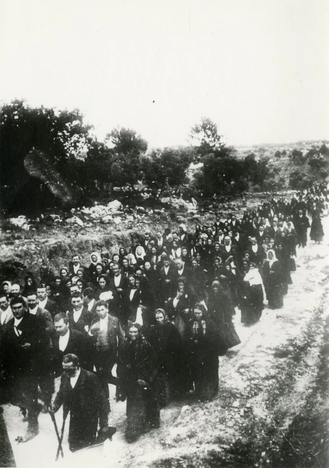1922 年走向法蒂瑪的朝聖者隊伍，穿著深色衣服，沿著土路前進