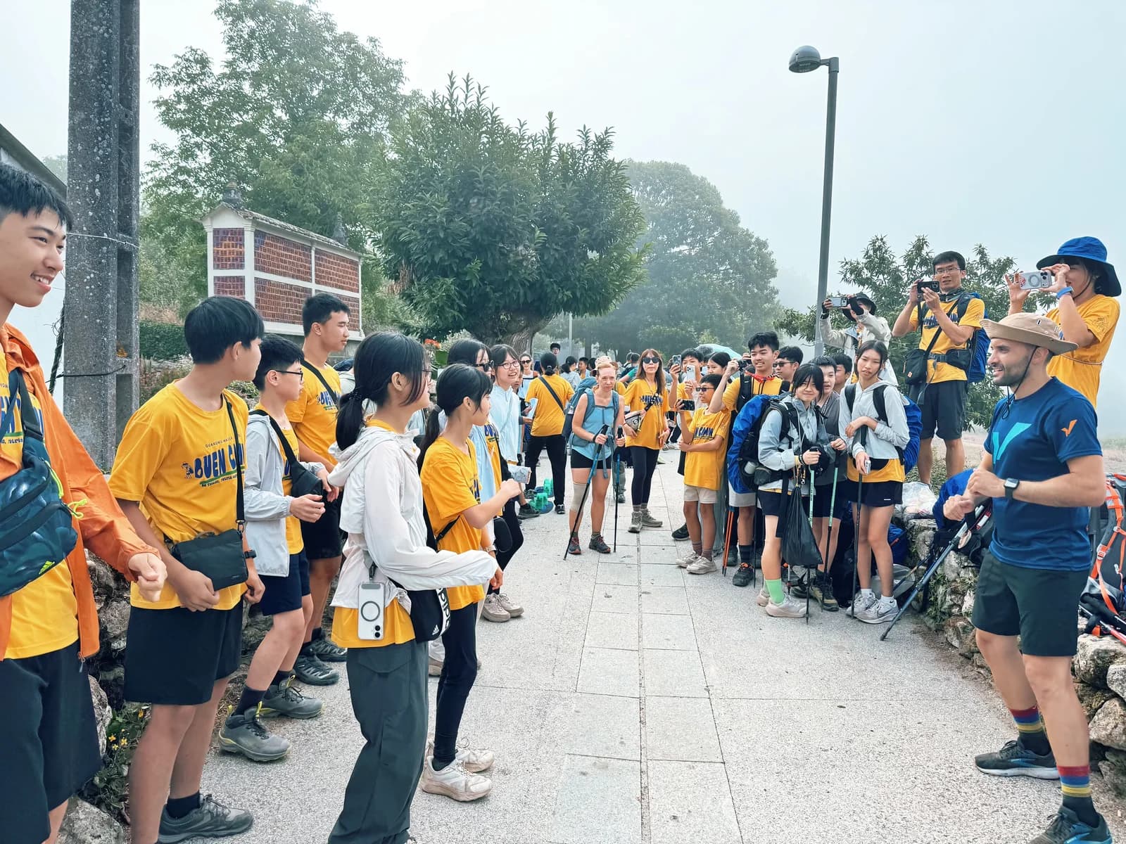 光武學生與外國朝聖者在路旁面對面交流，其他同學圍在一旁