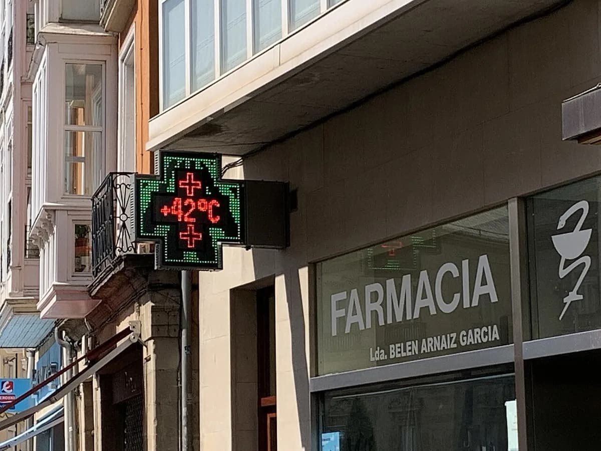 西班牙街上的藥局，牆上掛著綠色十字燈箱，顯示 42°C，下方是 FARMACIA 招牌