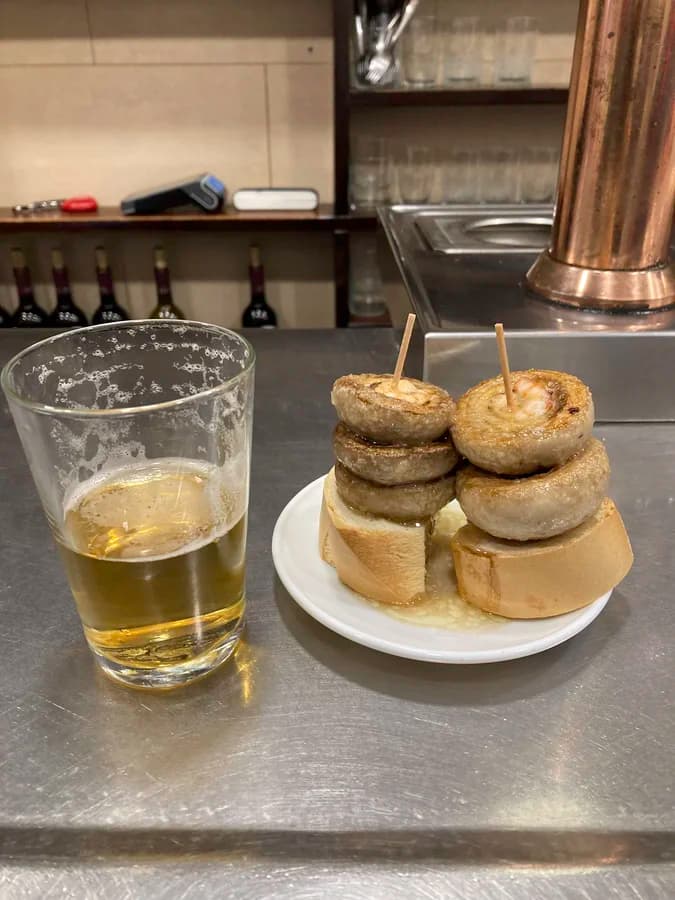 Bar Ángel 的招牌烤蘑菇 Champis，三顆蘑菇疊放在麵包上，搭配啤酒